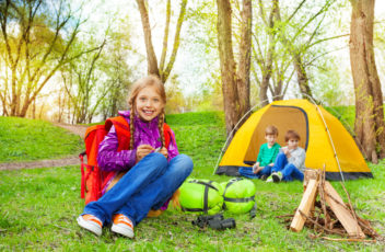 Happy children relax near the wooden bonfire, tent